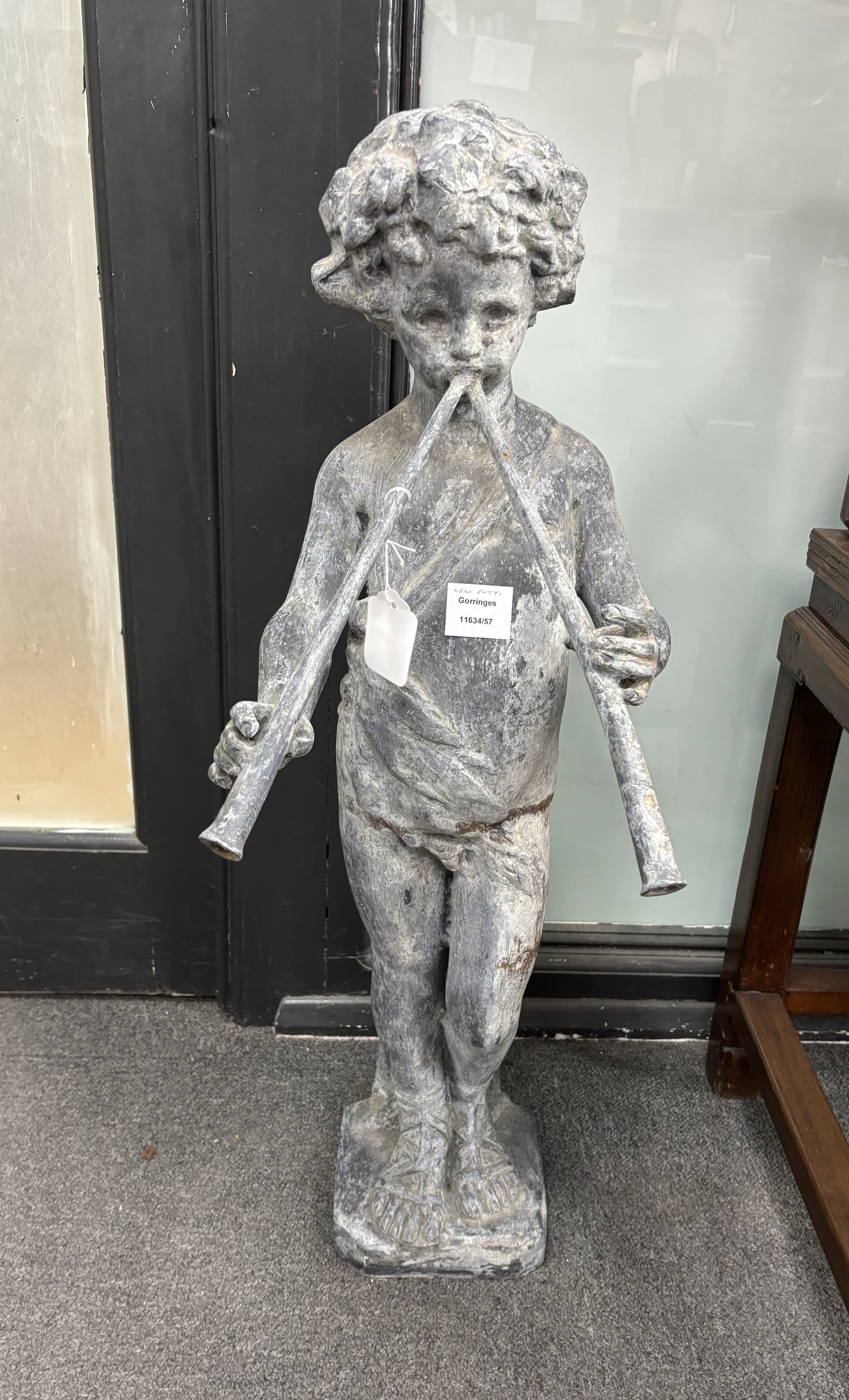 A lead model of a putti playing pipes, height 81cms